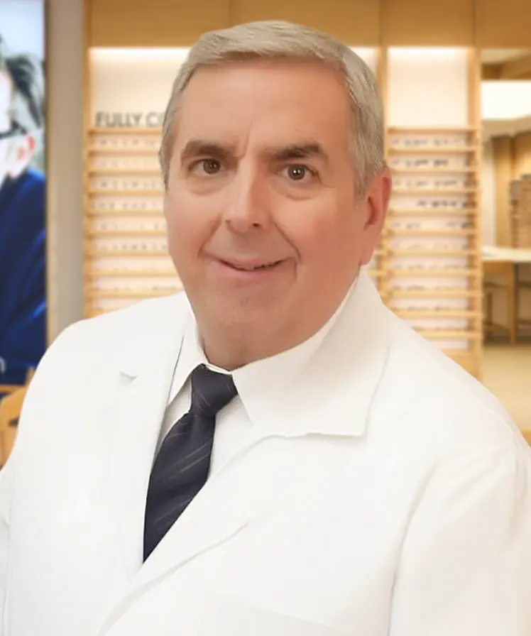 Dr. Joseph Herba wearing a white coat and smiling, stands inside an eyewear store.