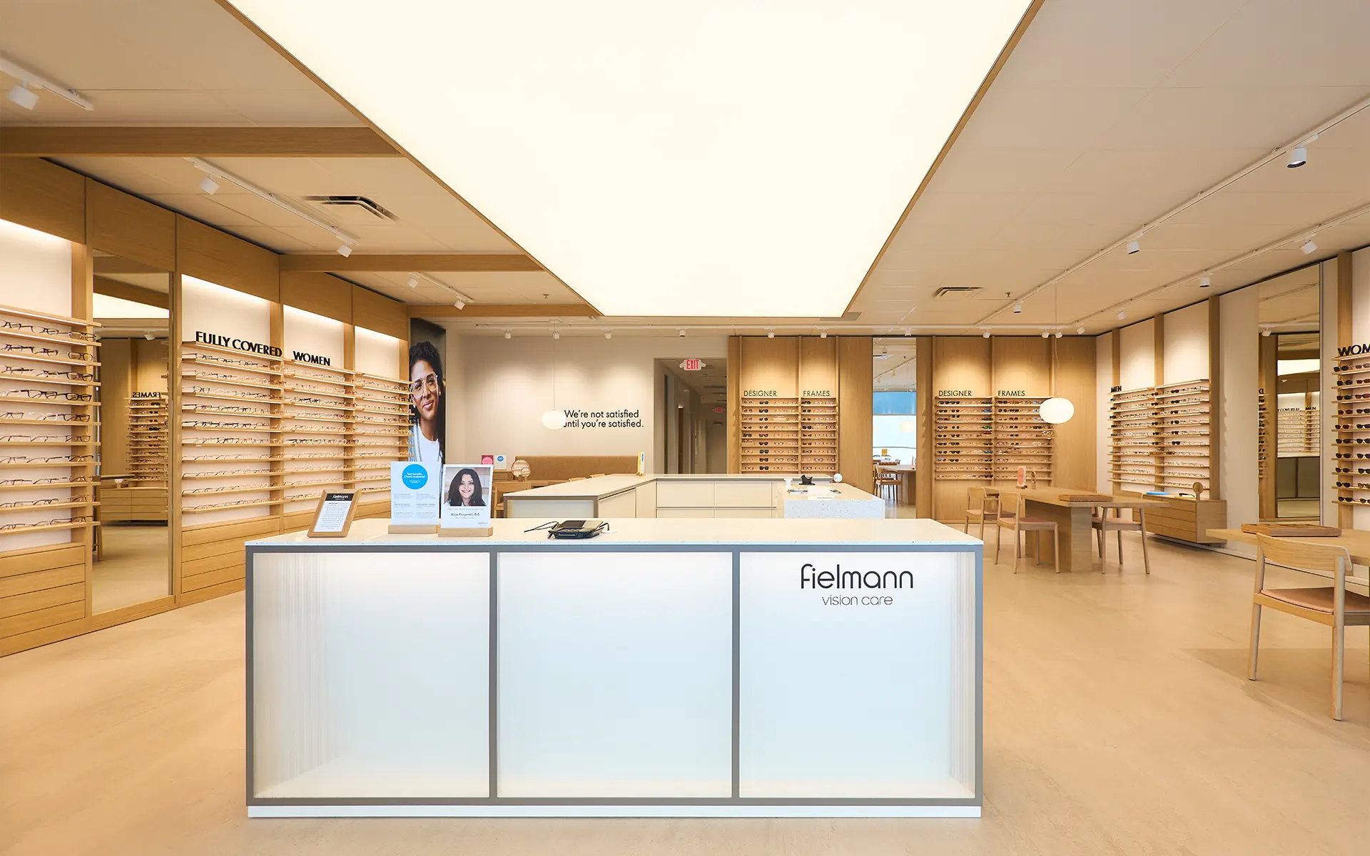 Modern eyewear store interior with displays of glasses on wooden racks, a bright reception desk, and stylish, minimalistic decor.