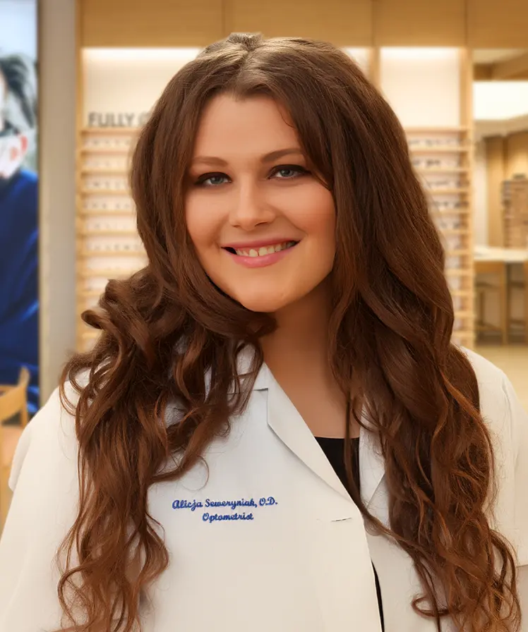 Dr. Alicja Fitzgerald wearing a white coat and smiling, stands inside an eyewear store.